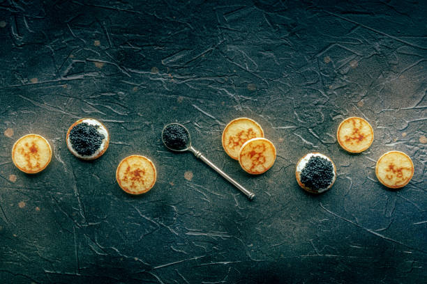 istock Blinis with black caviar and cream cheese overhead flat lay shot on black 1830664904