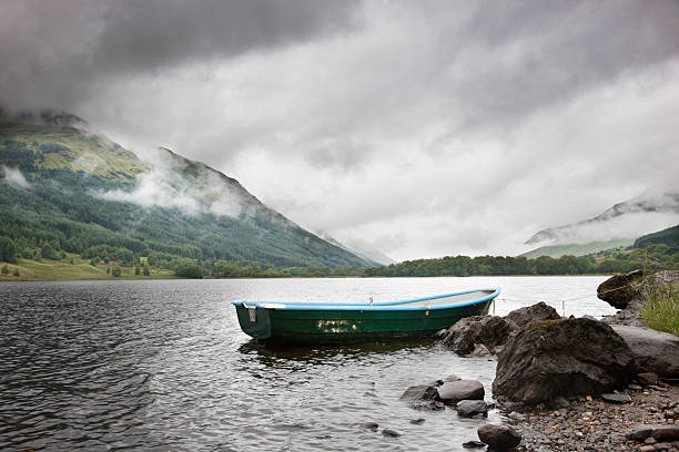 Rowing Boat On Loch Voil A small rowboat on the shore of Loch Voil in Scotland on a stormy day. loch voil stock pictures, royalty-free photos & images