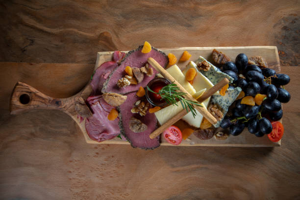 istock Appetizer platter with smoked meat, cheddar cheese and black grapes on cutting board 1830683963