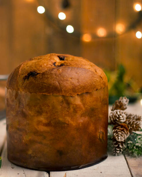 istock Christmas cake with dried fruit filling, pine cone Christmas decorations on the side, blurred lights in the background, white and natural wood 1830688519