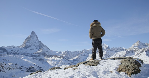 Panoramic landscape of Successful asian man celebrate and raising arms on mountain peak view point with iconic famous Matterhorn background. Swiss alps, Switzerland. Travel and Adventure concept.