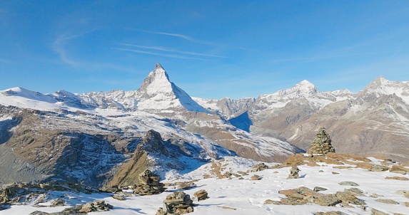 Majestic mountain peaks full of stacked rock hiker cairns with famous Matterhorn view background during winter in Switzerland. Swiss alps wonderful inspiring nature landscape.