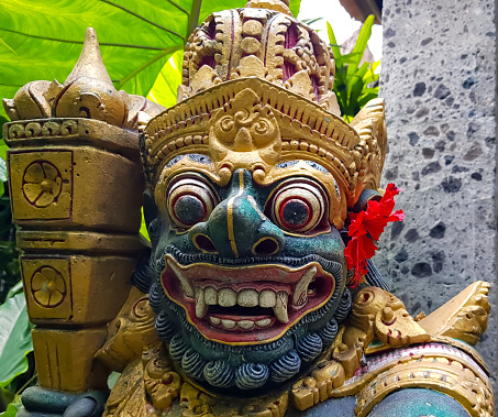 figure guarding the entrance to a Hindu temple, statue of sacred temple in Bali, balinese temple guardian, balinese gnome, Traditional Balinese statues or called Arca made of stone carvings in the form of gods, people or demons. Balinese sculpture in temple.