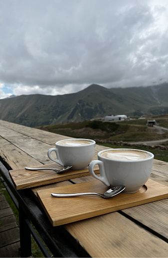 Two cups of coffee on a wooden table in a cafe. Coffee shop in the mountains.