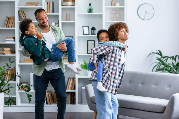 istock Happy parents with kids dancing in modern living room, having fun, playing active game, overjoyed mother and father with children siblings dancing to favorite music, jumping, celebrating event 1830698671