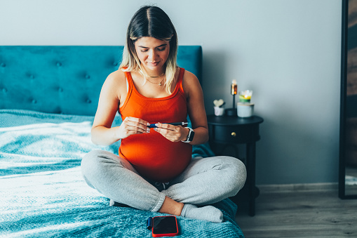 Pregnant young woman preparing insulin dosage on insulin pen before injecting in abdomen