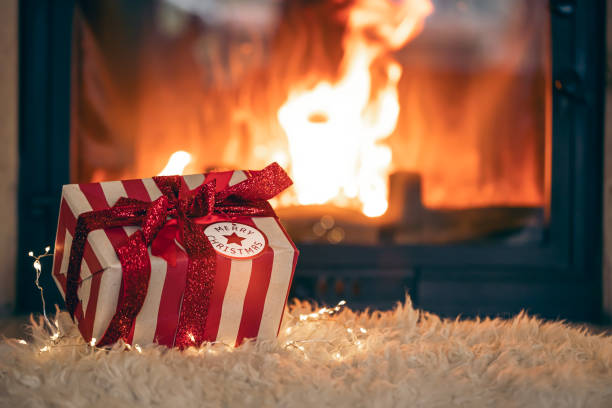 istock Christmas gift box by the fireplace, copy space. 1830712656