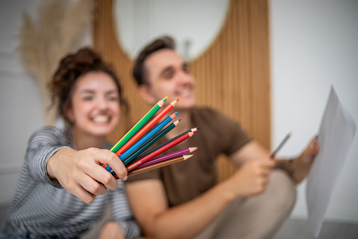 A young beautiful couple paint with wooden crayons, enjoy their life together and use their free time to have fun and learn new skills