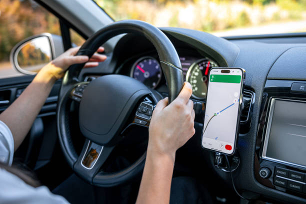 istock A woman in a car holds a mobile phone with a GPS navigation map. 1830743879