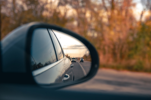 The view of the road in the car's rearview mirror, travel by personal car.