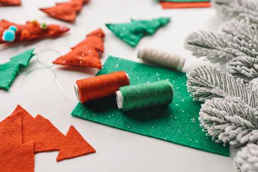 Process of hand made soft toys sewing with felt and needle for Christmas tree decoration.