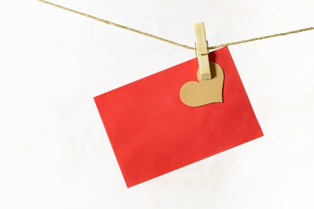 Red leaf with heart hanging from hemp rope. A wooden clothespin is holding a brown heart and a red sheet on a hemp cord. The background is whit. Love. clothespin wood stock pictures, royalty-free photos & images