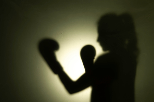 Boxing scene of a woman with a shadow falling.