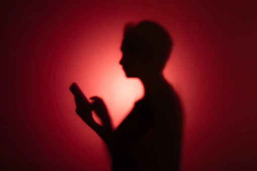 Silhouette of woman holding a smartphone.