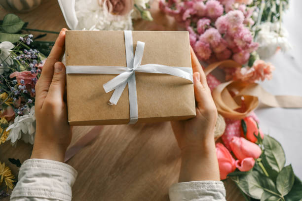 istock Gift box in hands with flowers at home 1830782526