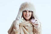 happy modern woman in winter coat and fur hat on white