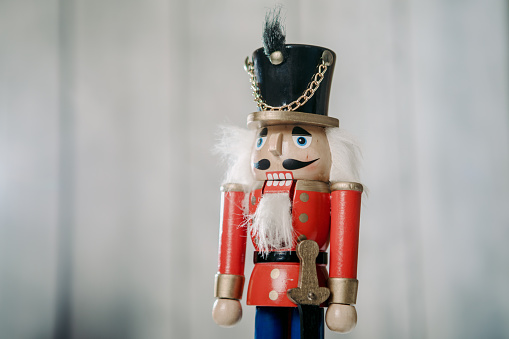 Two wooden Christmas Nutcrackers standing side by side. One  nutcracker is a drummer.  One figurine has black hair, and the other figurine has white hair.  Nutcrackers are used to crack open nuts, but can also be used as colorful Christmas decorations. The image is isolated on a white background.