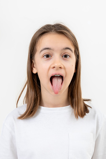 Portrait of a teenage girl showing her tongue isolated on a white background, health concept.