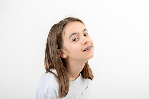 Caucasian teenage girl with braces on her teeth smiles on a white background isolated.