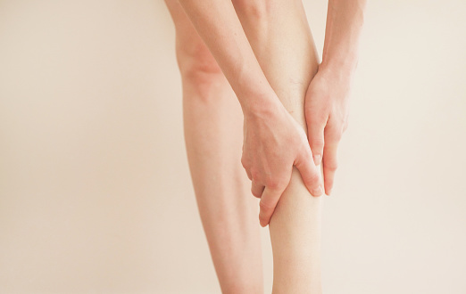 A young girl massages her thin and long tired legs at home. Prevention of varicose veins.