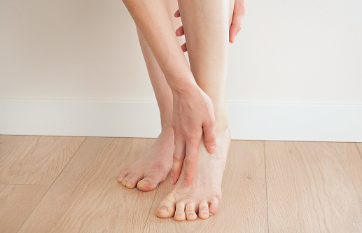 A young girl massages her thin and long tired legs at home. Prevention of varicose veins.