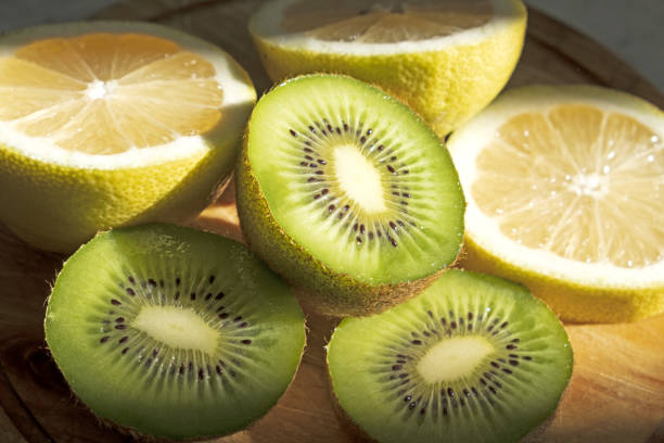 Plate with fresh cut kiwi and lemmon  on light background.