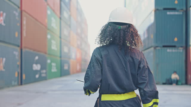 Rear view A woman engineer walking in the Container Terminal