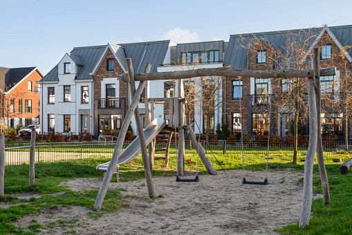 Multicolored Children playground, outdoors play equipment, jungle gym with slide surrounded by a wooden fence, trees in the background. Soft flooring. Galicia, Spain.