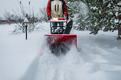 Adult man removing snow with snowblower at heavy snowfall