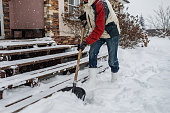 Adult man removing snow from porch using shovel
