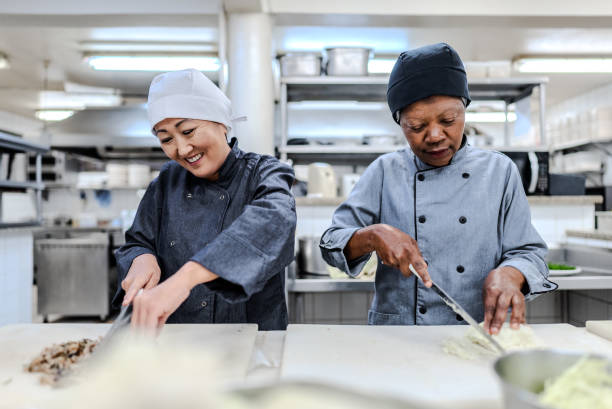istock Colleagues talking while chopping food in a commercial kitchen 1830822604
