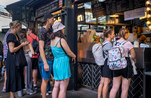 Groups of people queuing at a fish and chip stall in Borough Market, Southwark, South East London.