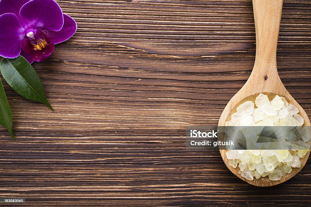 Cappuccino sea salt. Sea salt on wooden spoon, purple orchid on wooden background Agreement Stock Photo
