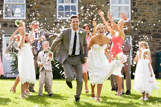 Guests Throwing Confetti Over Bride And Groom Guests Throwing Confetti Over Bride And Groom As They Run Towards Camera guest photos stock pictures, royalty-free photos & images