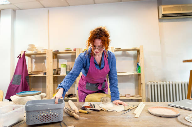 istock Woman working in pottery studio workshop making bowl from clay. 1830844576
