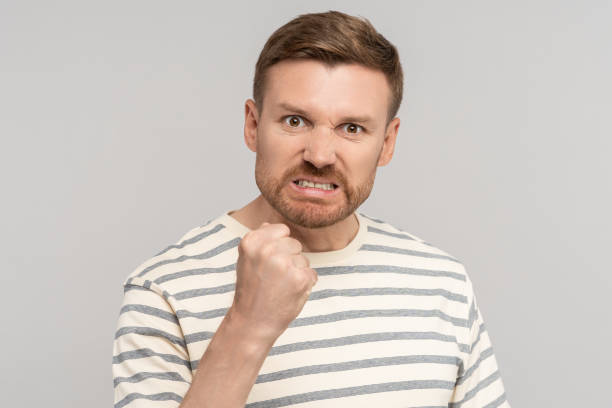 istock Angry aggressive middle aged man clenched fist has evil face looking at camera on grey background. 1830878270