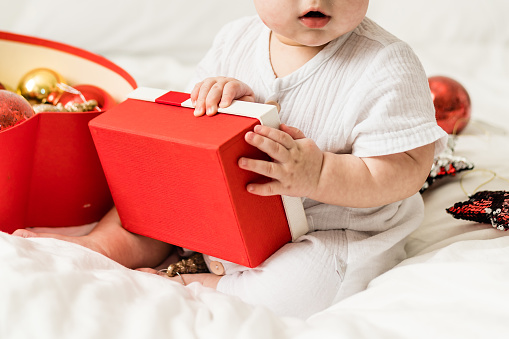 Adorable baby boy playing with Christmas baubles and new year gift. Winter holidays celebration and festive