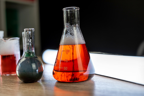 Glass laboratory flask and beaker with liquids for analys or experiment in desk. Chemical experiments