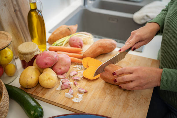istock Unrecognizable woman chopping fresh raw sweet potato 1830905521