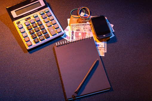 Notepad and calculator. Money on the table. Smartphone and notepad. Trader. View from above.