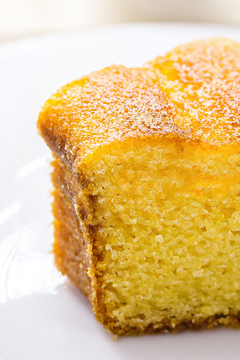 small slice of cornmeal cake, typical Brazilian rural cake made with corn flour, with hot coffee in the background, Brazilian breakfast