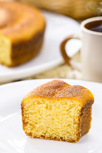 small slice of cornmeal cake, typical Brazilian rural cake made with corn flour, with hot coffee in the background, Brazilian breakfast