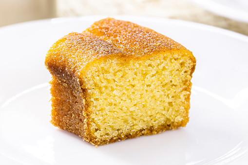 small slice of cornmeal cake, typical Brazilian rural cake made with corn flour, with hot coffee in the background, guava jam in the background with cheese