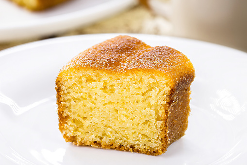 small slice of cornmeal cake, typical Brazilian rural cake made with corn flour, with hot coffee in the background, Brazilian breakfast