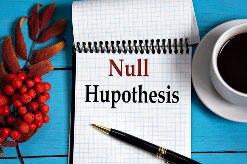 NULL HUPOTHESIS - words in a white notebook on a wooden blue background with a rowan branch and a fragment of a cup of coffee. Medical concept