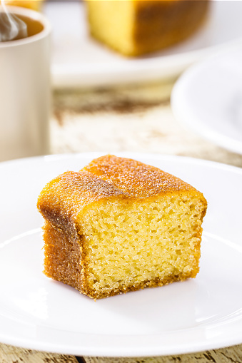 small slice of cornmeal cake, typical Brazilian rural cake made with corn flour, with hot coffee in the background, guava jam in the background with cheese