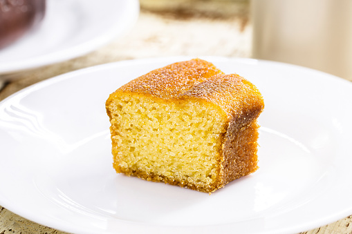 small slice of cornmeal cake, typical Brazilian rural cake made with corn flour, with hot coffee in the background, guava jam in the background with cheese