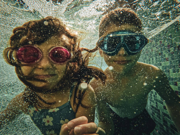istock Brother and sister swimming underwater 1830944806