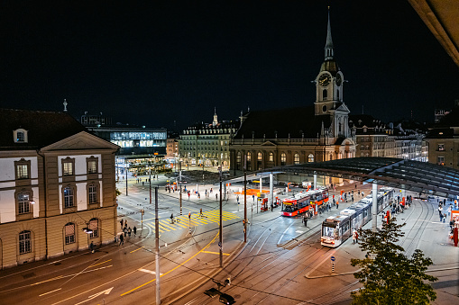 Main railway station (Bahnhof Bern) and Church of the Holy Spirit at night in Bern, Switzerland.