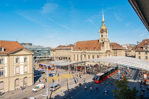 Busy day on Bern main railway station (Bahnhof Bern) and Church of the Holy Spirit in Switzerland.